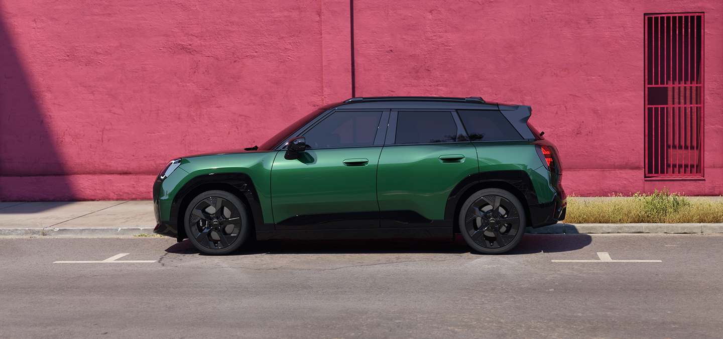 Sidovy av en helt elektrisk MINI Aceman i British Racing Green och svart tak på en gata.