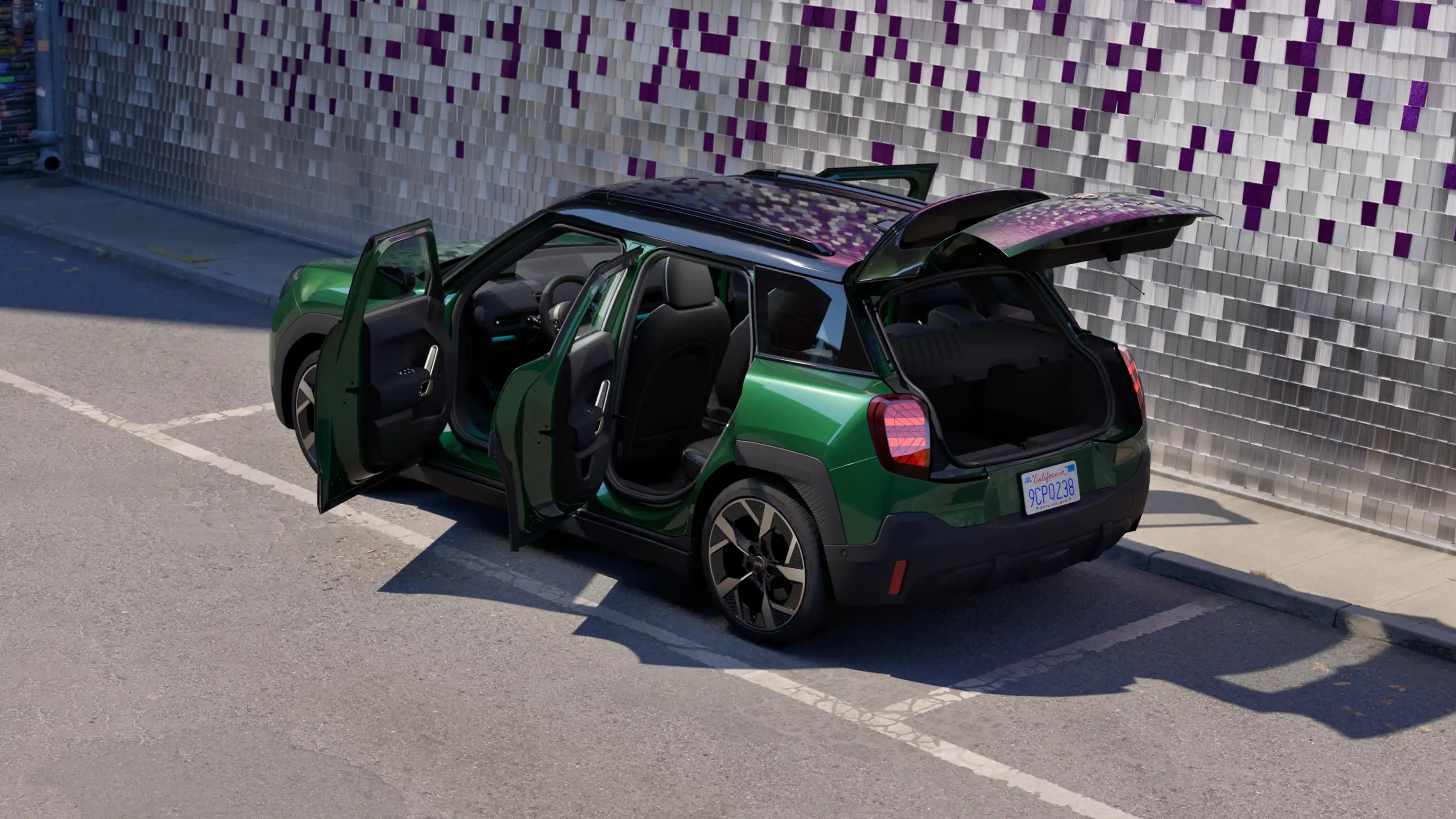 Vy bakifrån av en helt elektrisk MINI Aceman i British Racing Green på parkeringsplats med alla dörrar öppna och färgad vägg i bakgrunden