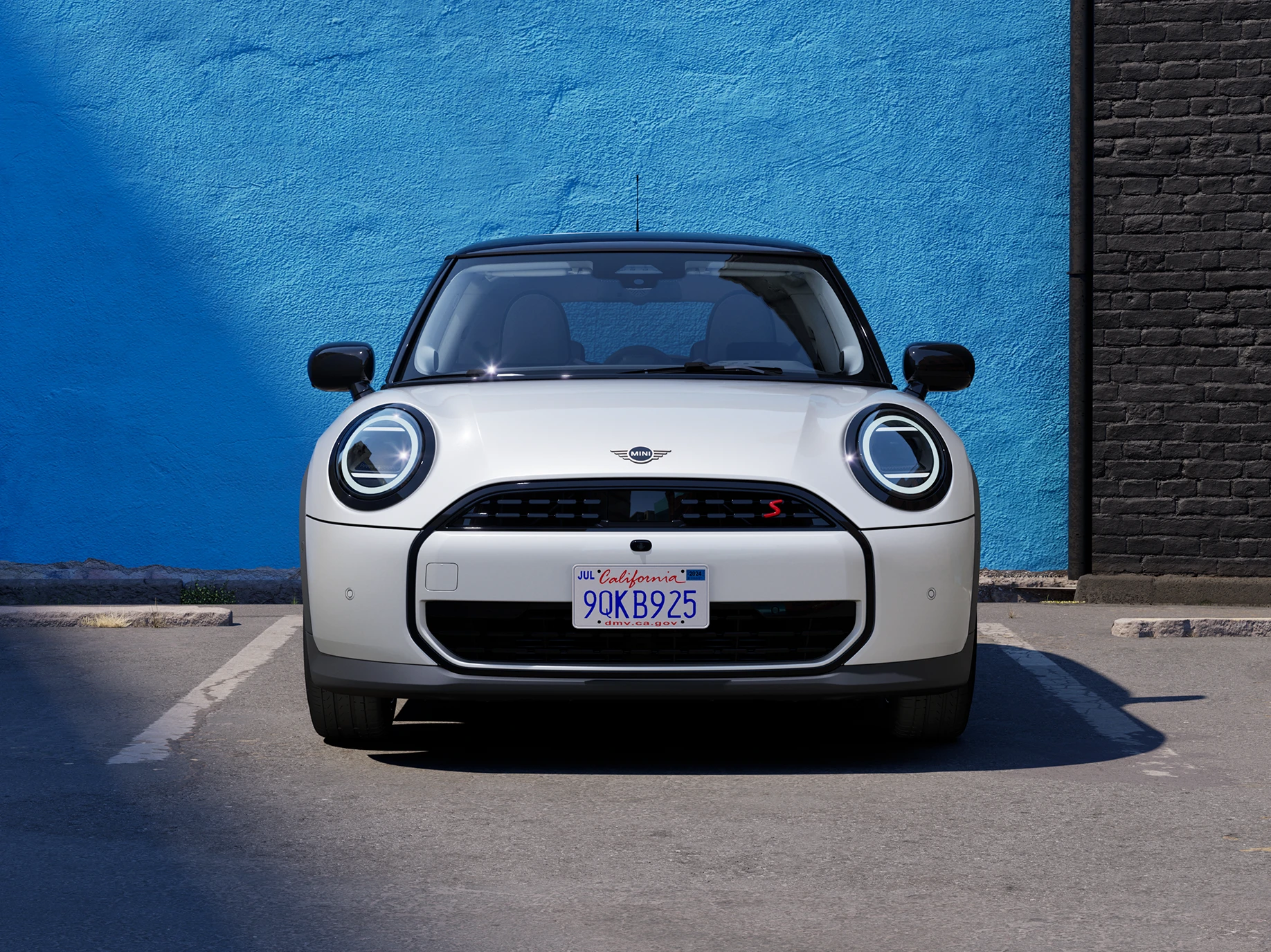 Vy framifrån av en MINI Cooper i Nanuq White med svart tak som parkerar.