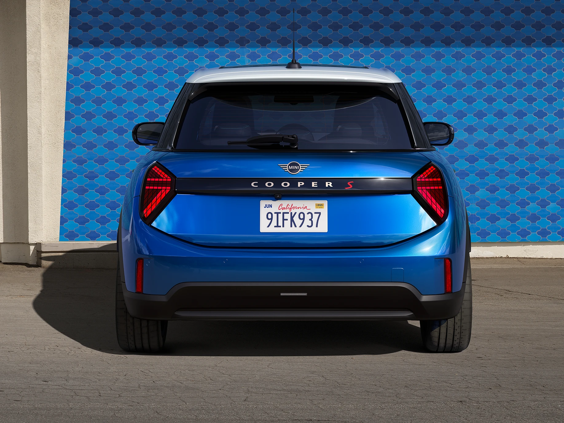 Vy bakifrån av MINI Cooper 5-dörrars i Icy Sunshine Blue och flerfärgat tak i blått.