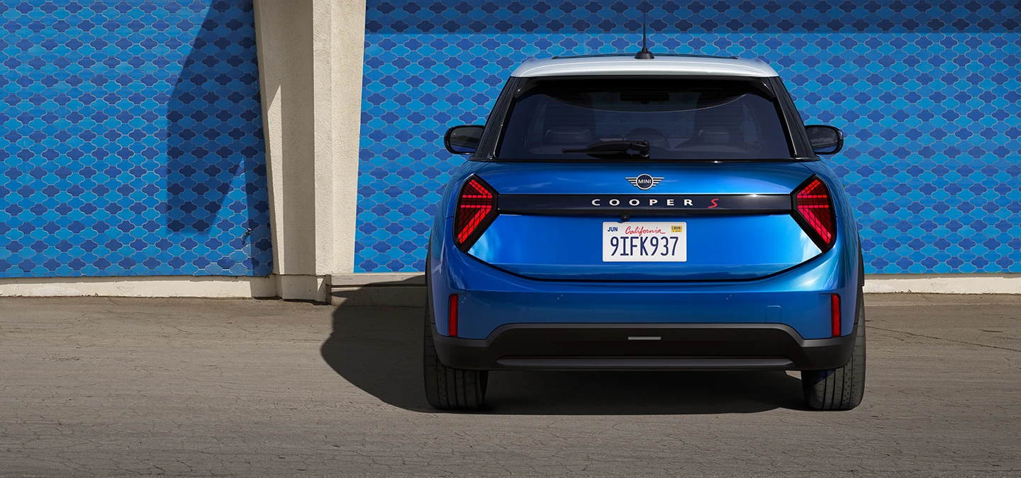 Vy bakifrån av MINI Cooper 5-dörrars i Icy Sunshine Blue och flerfärgat tak i blått.