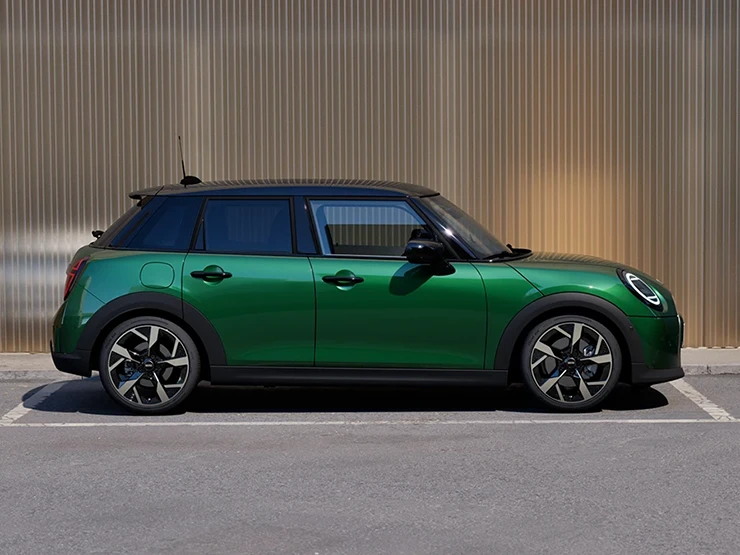 Sidovy av MINI Cooper 5-dörrars i British Racing Green och svart tak som parkerar.
