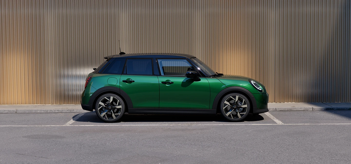 Sidovy av MINI Cooper 5-dörrars i British Racing Green och svart tak som parkerar.