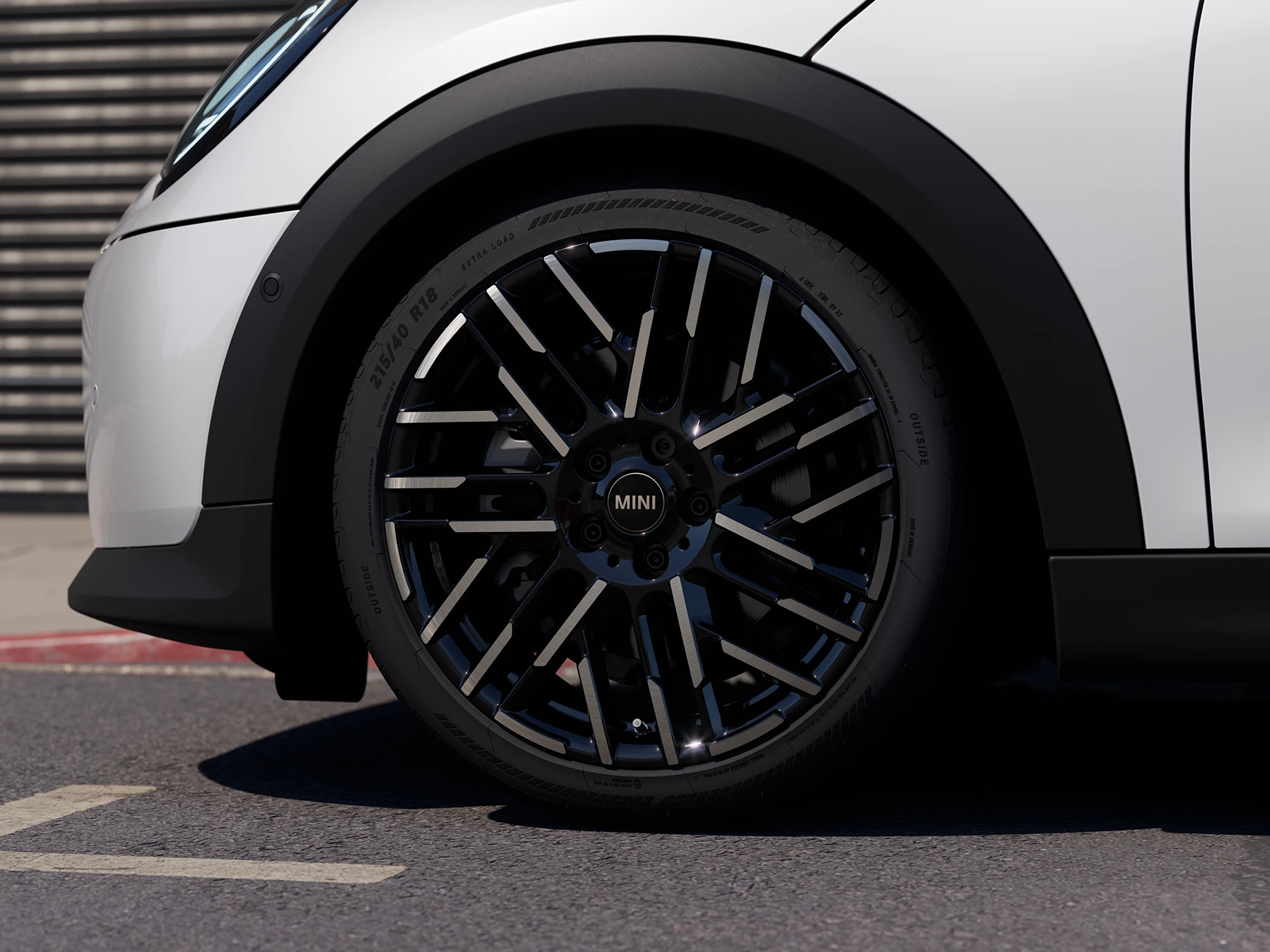 Närbild på MINI Cooper 5-dörrars i Nanuq White med 2-färgade fälgar med Night Flash-ekrar.