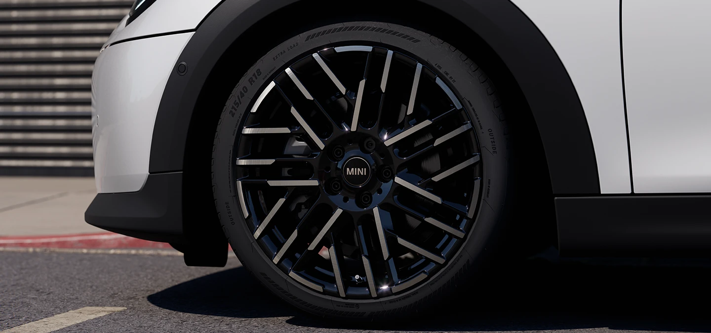 Närbild på MINI Cooper 5-dörrars i Nanuq White med 2-färgade fälgar med Night Flash-ekrar.