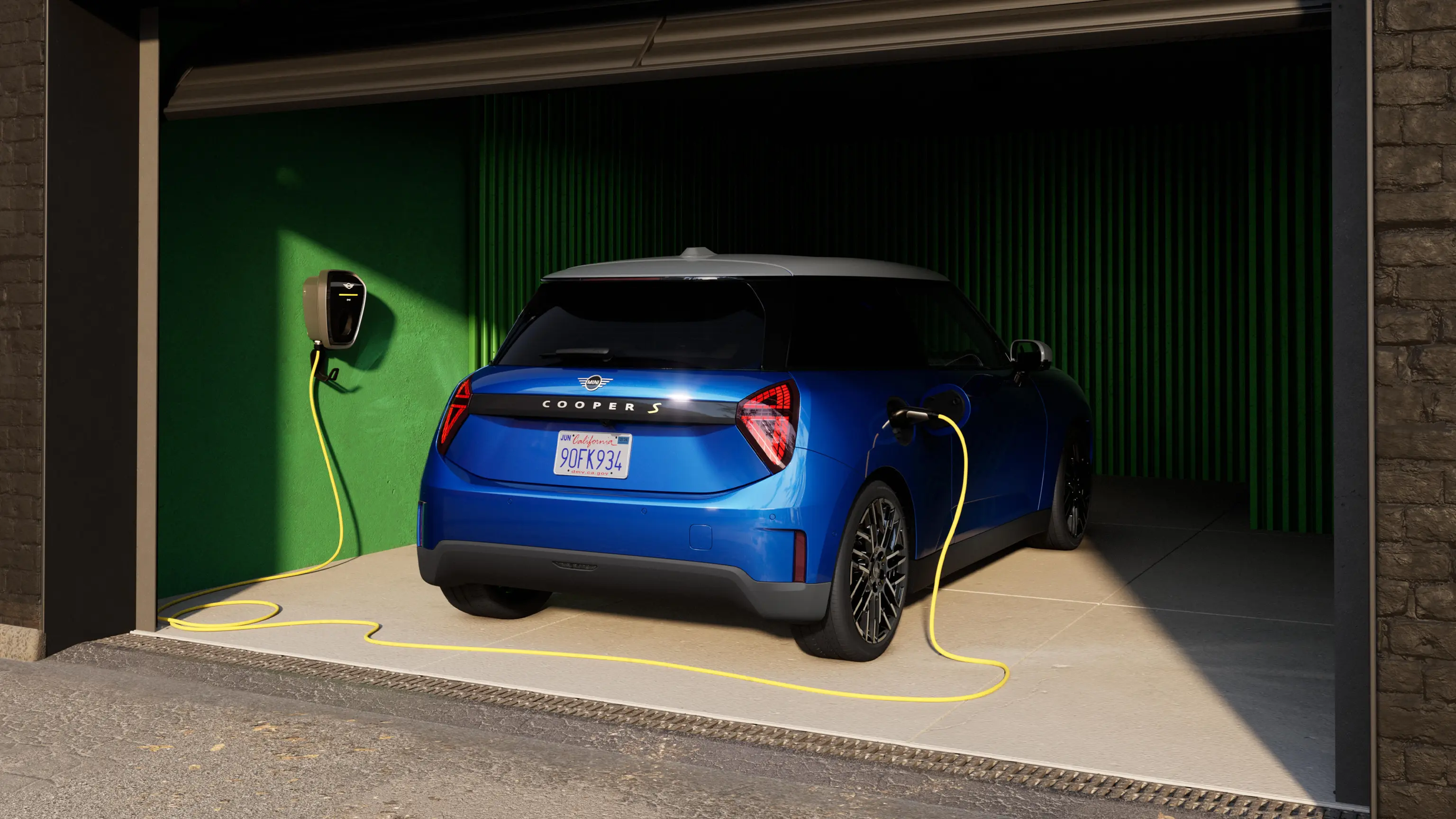 Helt elektriska MINI Cooper i Blazing Blue sedd bakifrån med laddkabel i garage