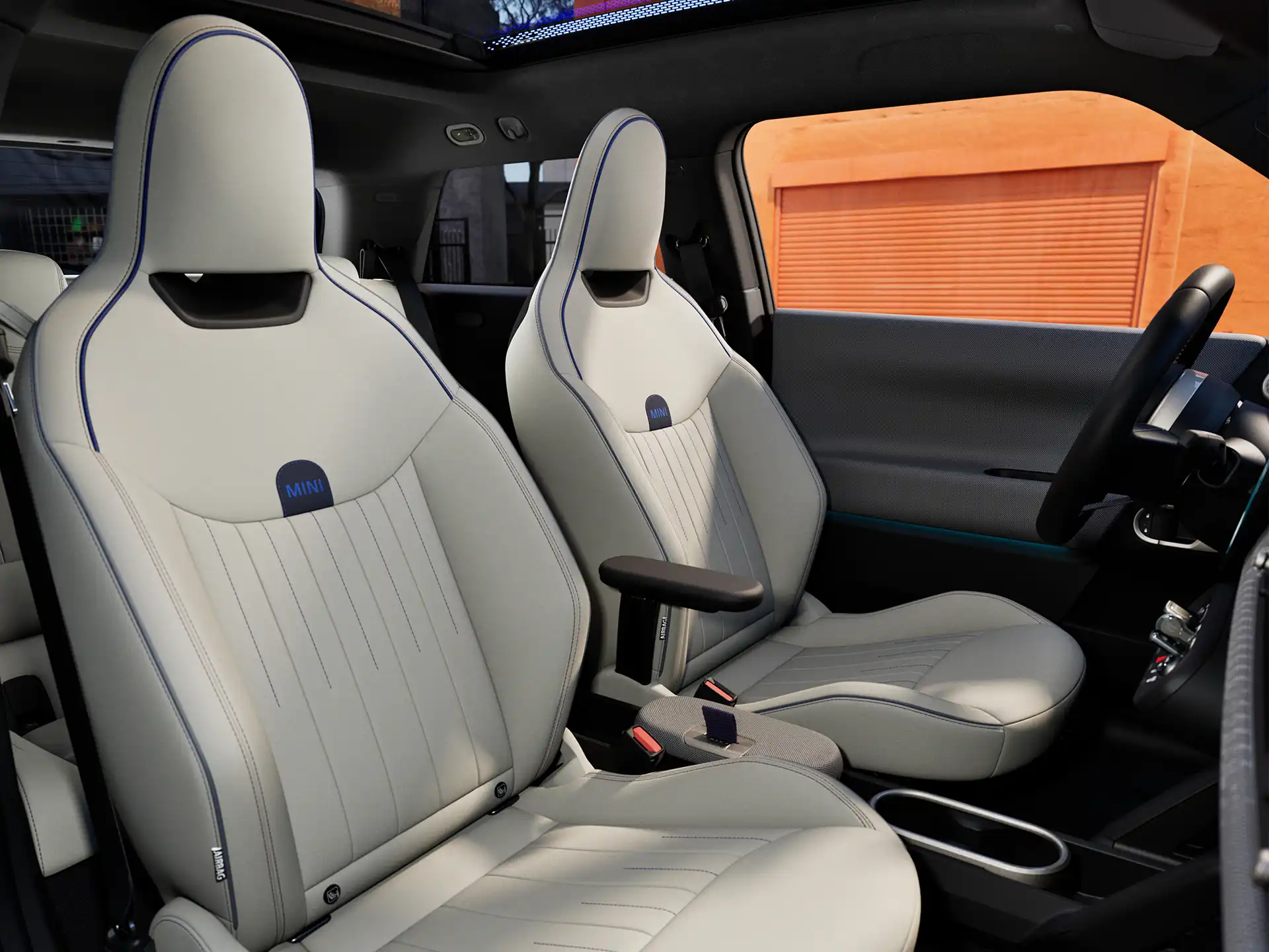 Bild på kupén i helt elektriska MINI Cooper som visar instrumentpanelen, ratten, den runda displayen, panoramaglastaket och framsätenas ryggar