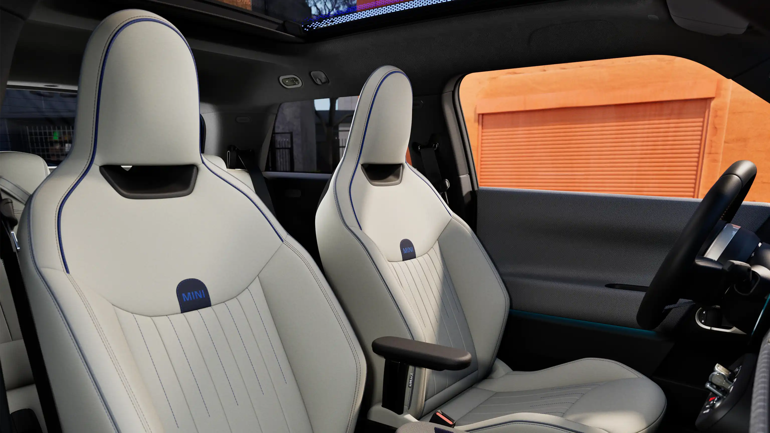 Bild på kupén i helt elektriska MINI Cooper som visar instrumentpanelen, ratten, den runda displayen, panoramaglastaket och framsätenas ryggar