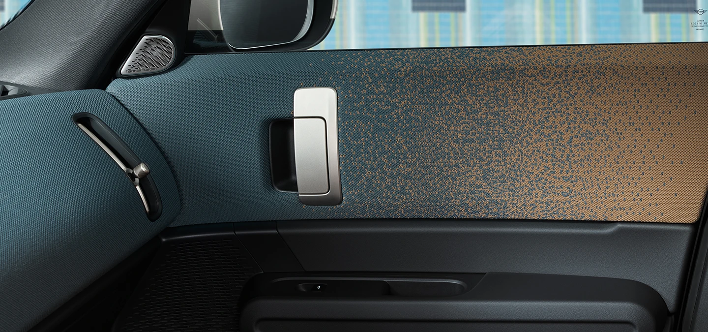 Närbild av inredningen i en helt elektrisk MINI Countryman med fokus på dörren och instrumentpanelen.