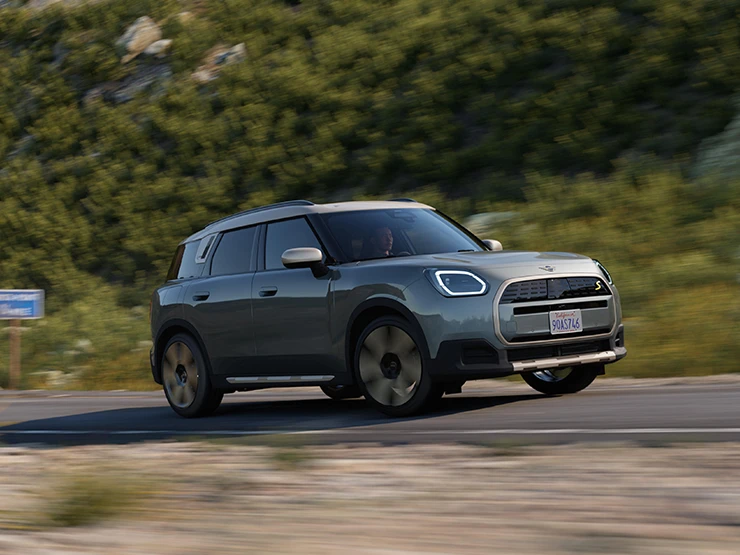 Sidovy av en helt elektrisk MINI Countryman i Smokey Green med tak i Vibrant Silver under körning.