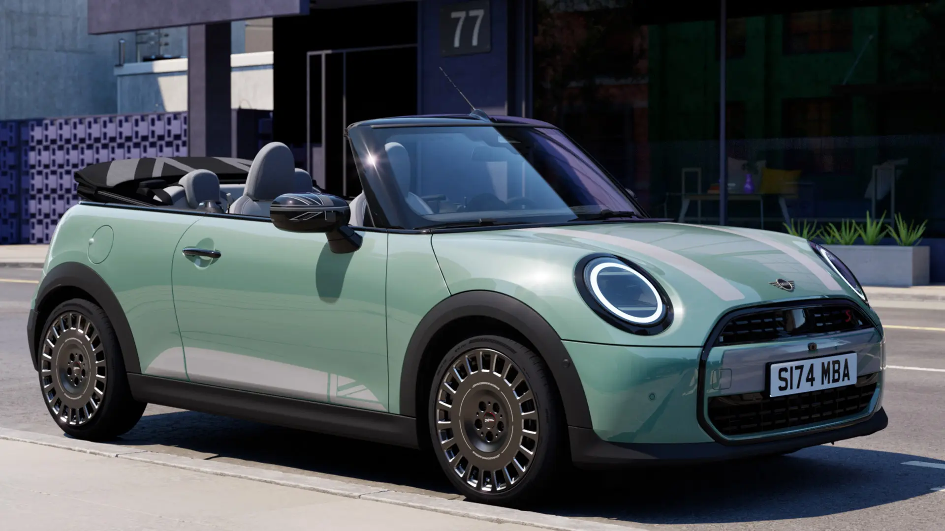 Vy snett framifrån av MINI Cabriolet i Ocean Wave Green med MINI Heritage motorhuvsdekaler i vitt. 