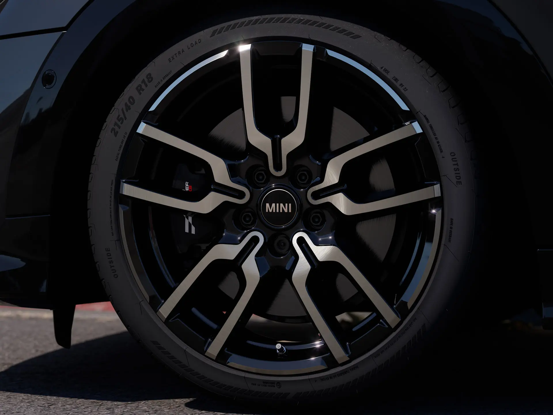 Närbild på JCW Lap Spoke lättmetallfälg som visar dess distinkta öppna ekerdesign i Jet Black-finish. 