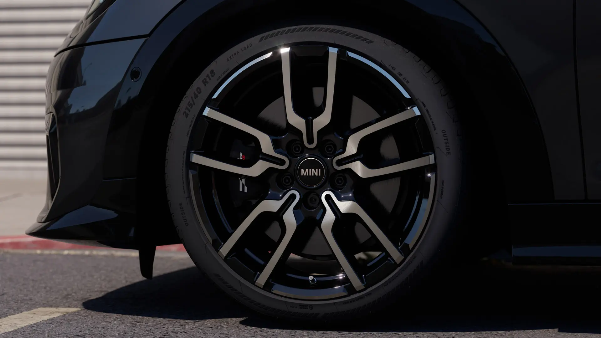Närbild på JCW Lap Spoke lättmetallfälg som visar dess distinkta öppna ekerdesign i Jet Black-finish. 