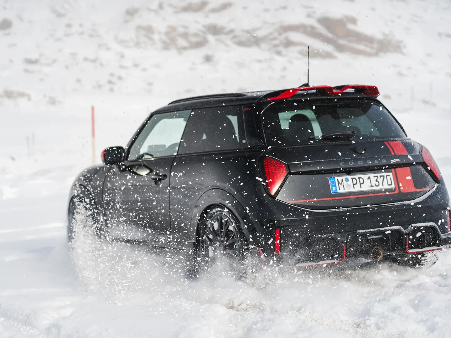 Vy bakifrån av en MINI Cooper JCW som kör genom snön.