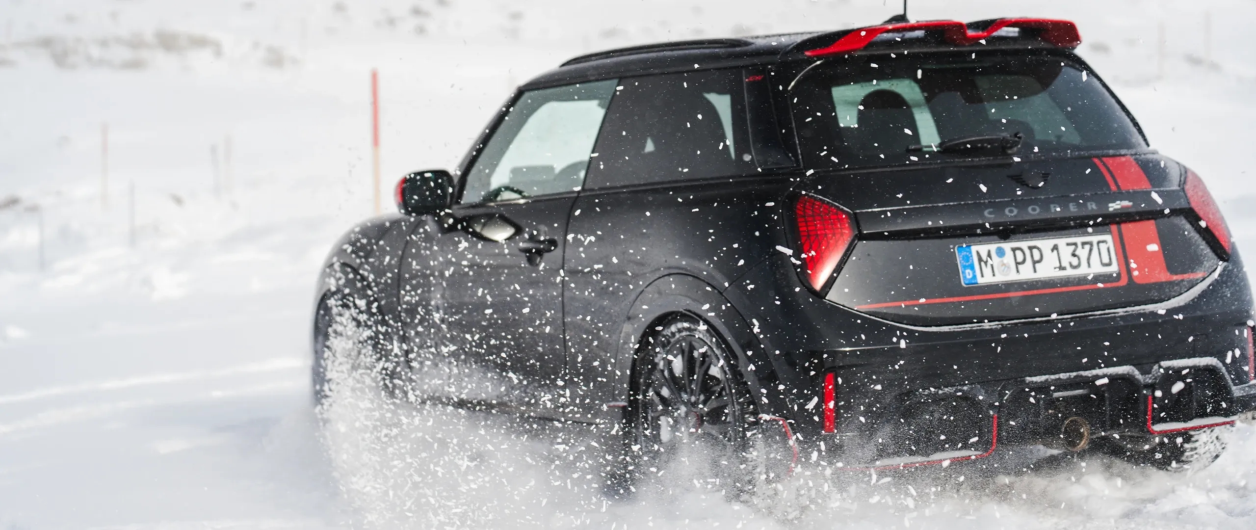Vy bakifrån av en MINI Cooper JCW som kör genom snön.