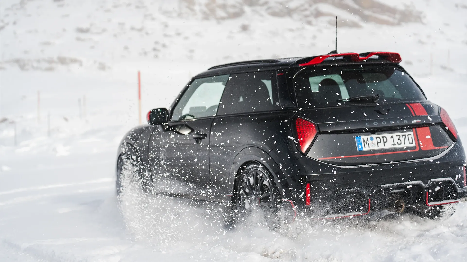 Vy bakifrån av en MINI Cooper JCW som kör genom snön.