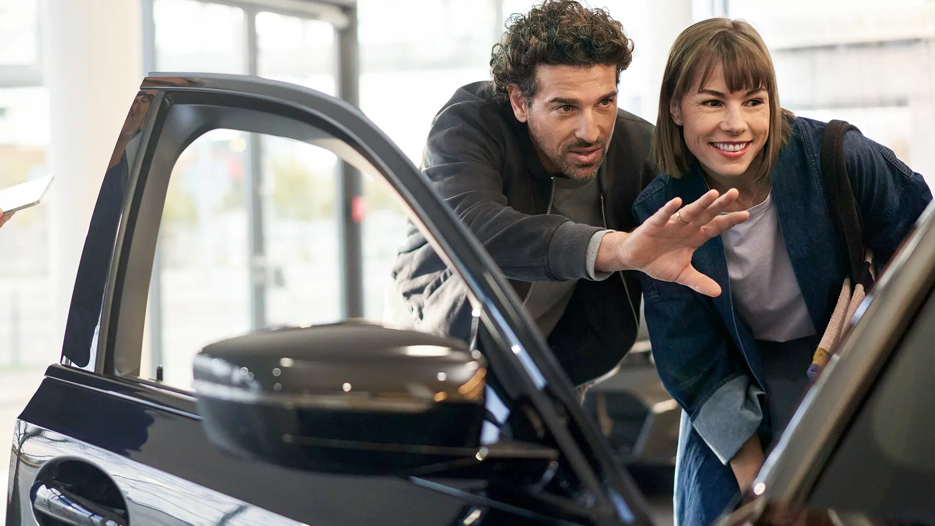 MINI inomhus hos en MINI återförsäljare med en expert som ger rådgivning till en kund och förklarar detaljer i kupén.