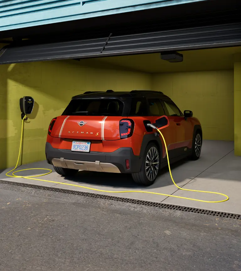 Helt elektriska MINI Aceman S laddas med MINI Wallbox Plus, sedd bakifrån, parkerad i garage.