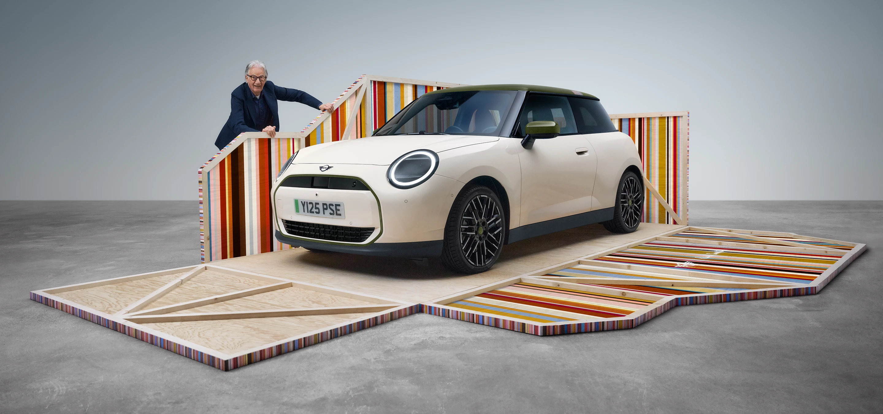 Sidovy framifrån av helt elektriska MINI Cooper Paul Smith Edition i Inspired White med designer Paul Smith
